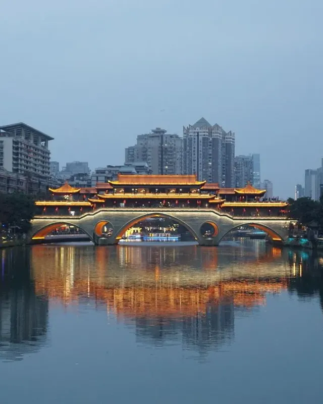 Illuminated Anshun Bridge reflected in the Jin River at dusk in Chengdu