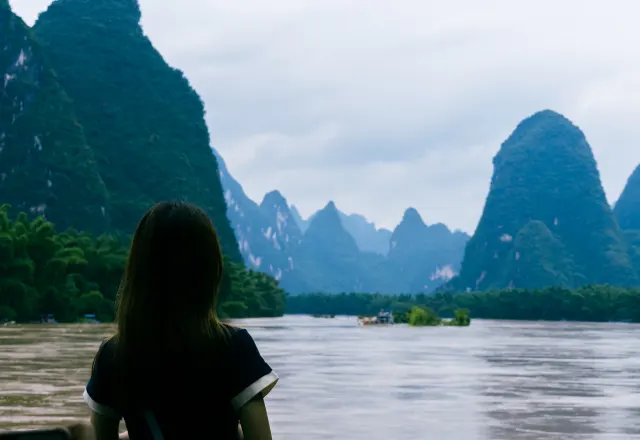 A traveller beside the Li River beneath limestone peaks in Yangshuo, Guilin