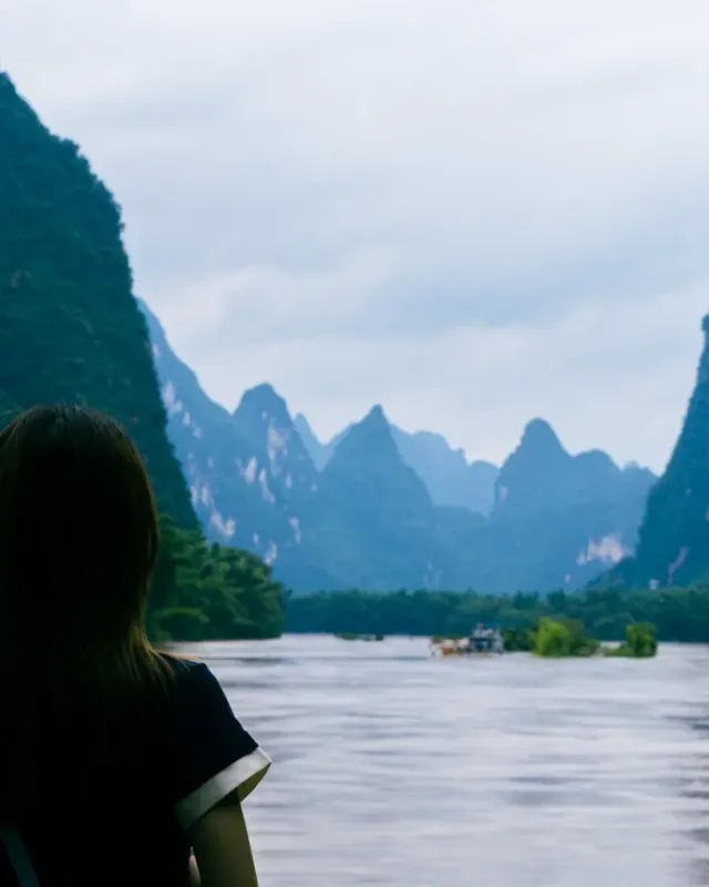 A traveller beside the Li River beneath limestone peaks in Yangshuo, Guilin