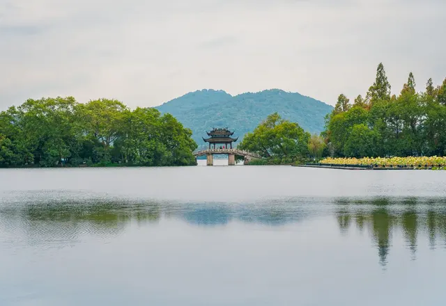 A pavilion on Hangzhou West Lake framed by trees and distant green hills