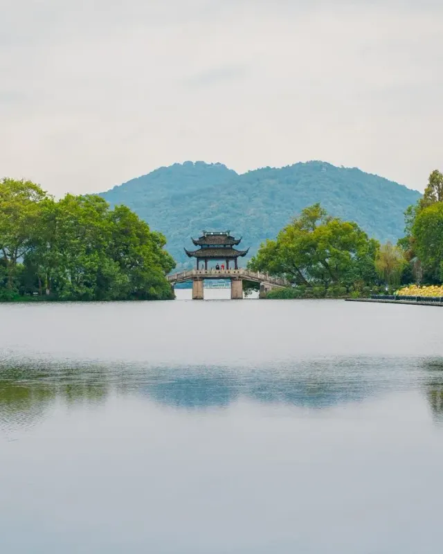 A pavilion on Hangzhou West Lake framed by trees and distant green hills