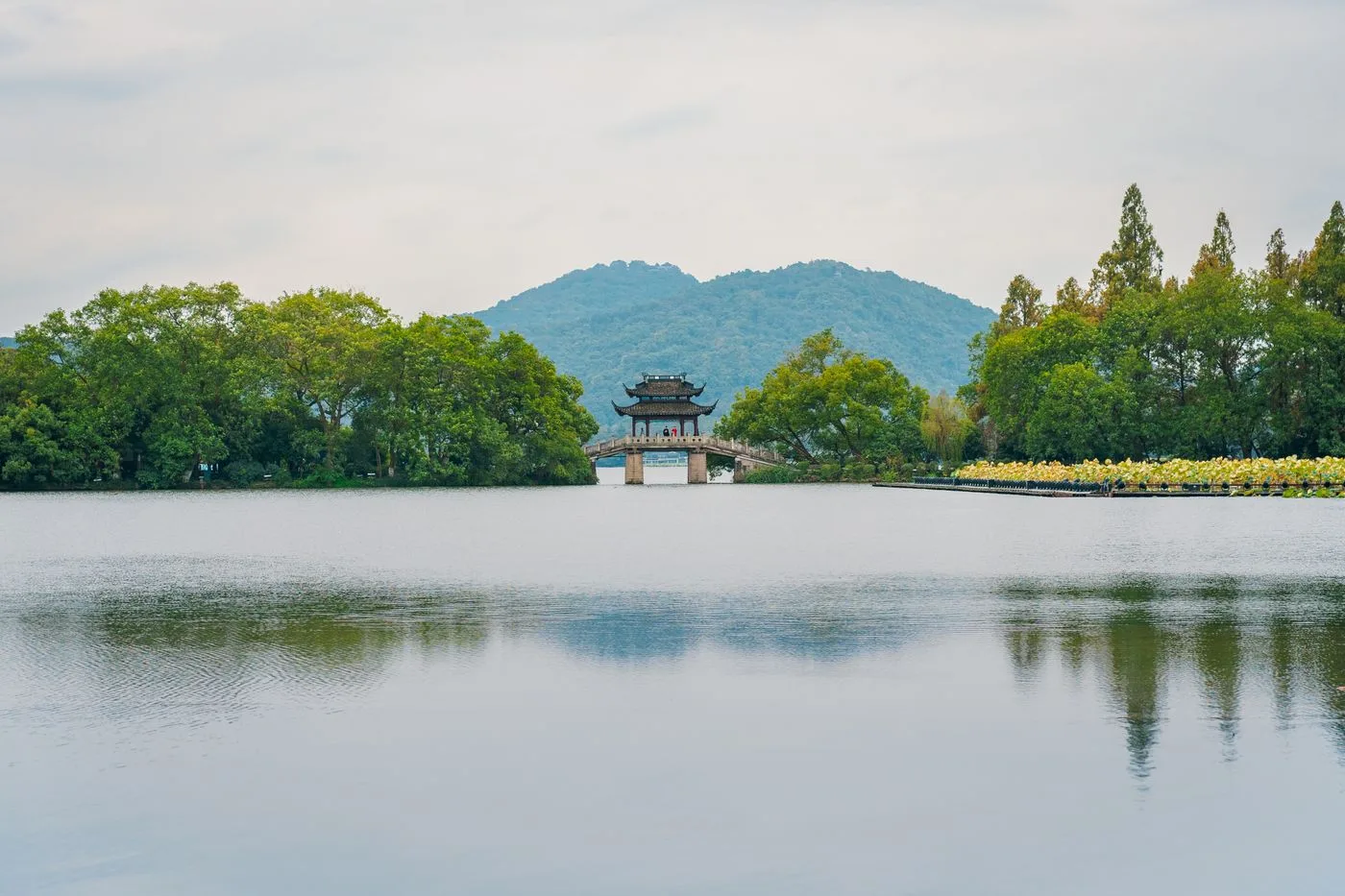 A pavilion on Hangzhou West Lake framed by trees and distant green hills