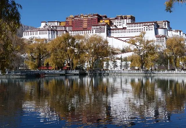The white and red buildings of the Potala Palace reflected in water in Lhasa