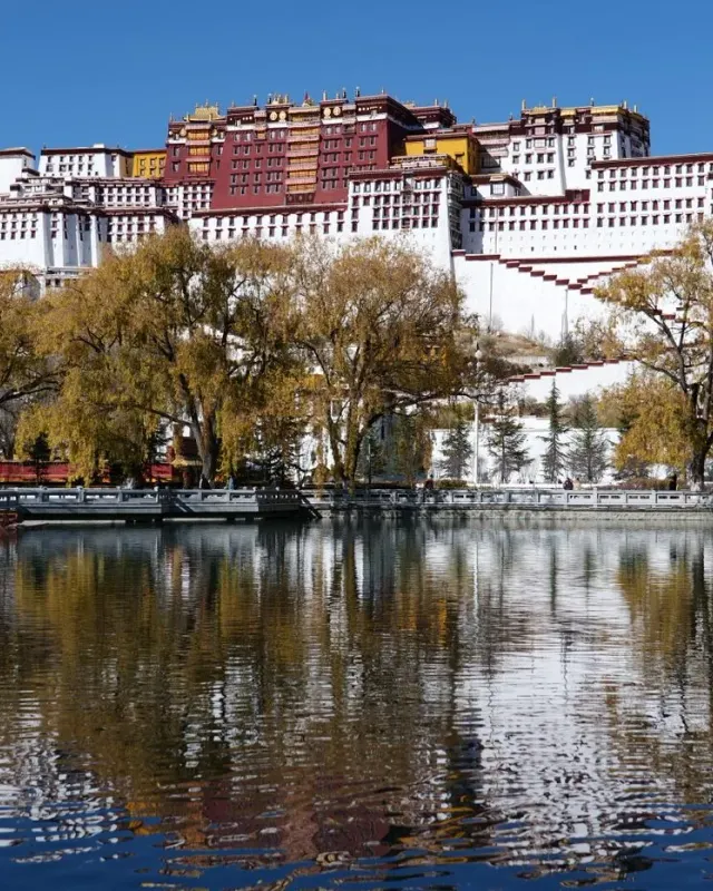 The white and red buildings of the Potala Palace reflected in water in Lhasa