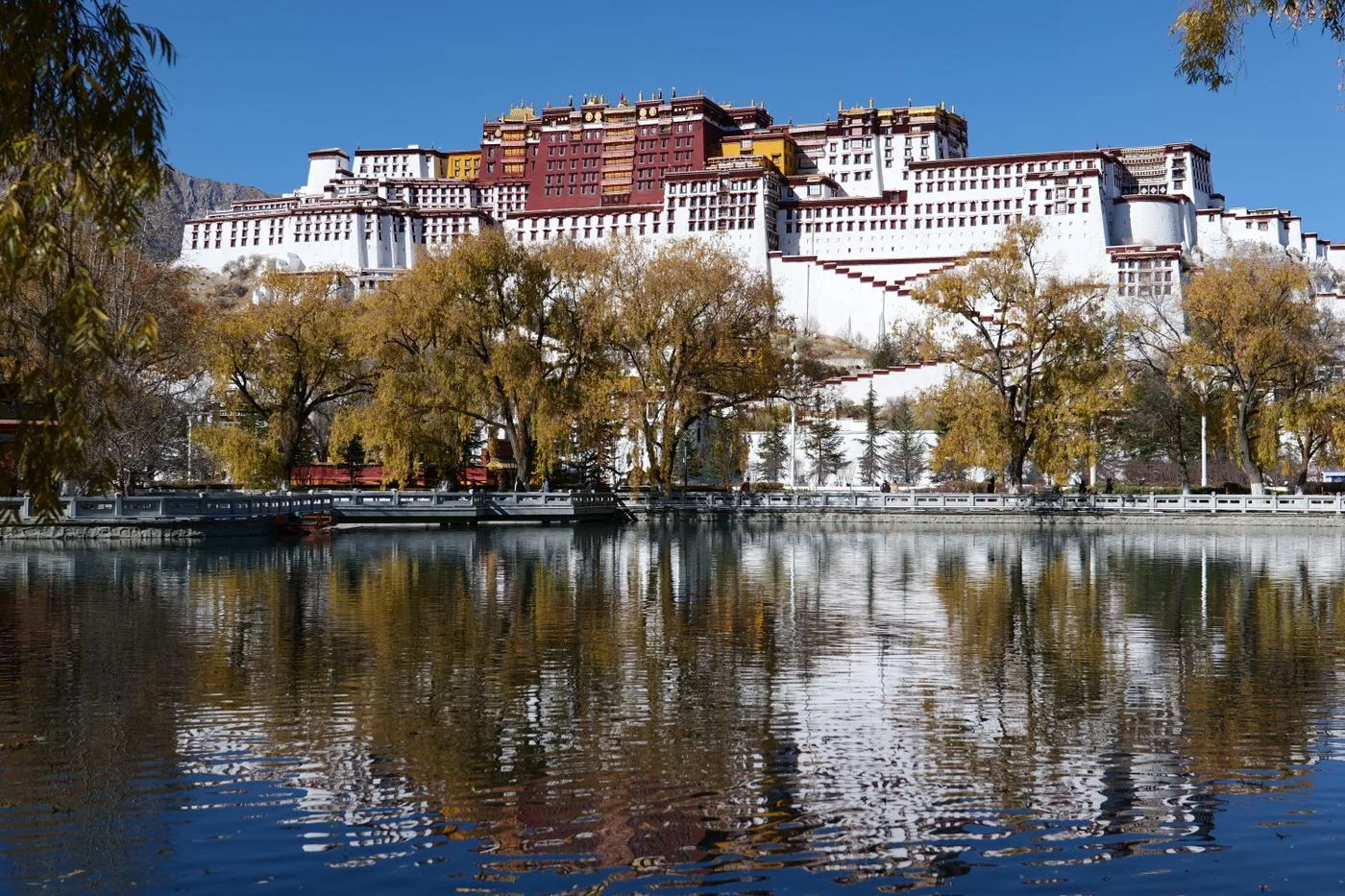 The white and red buildings of the Potala Palace reflected in water in Lhasa