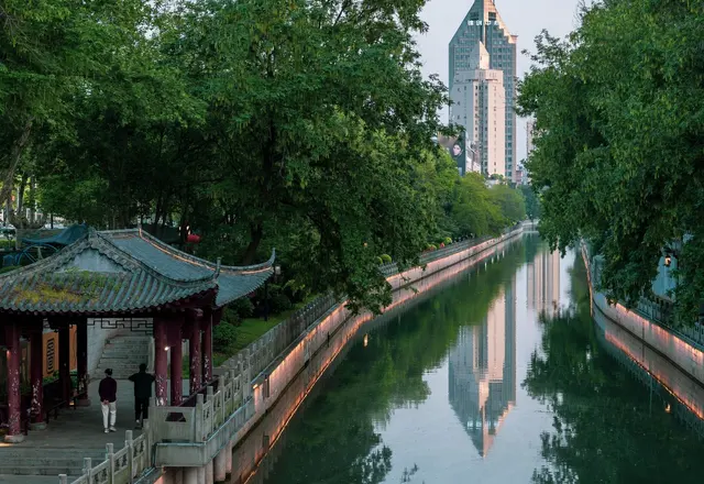 A traditional pavilion beside the Qinhuai River with modern buildings beyond, Nanjing