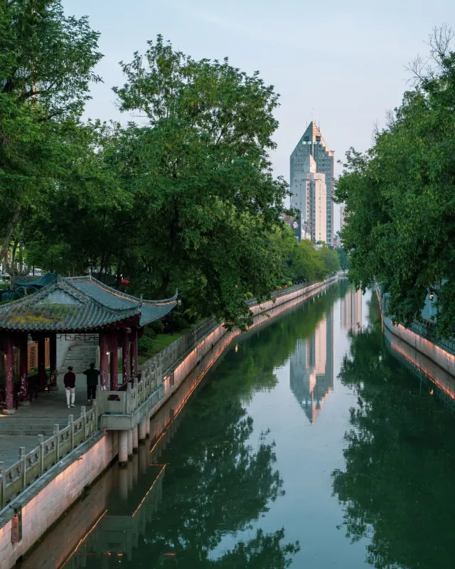 A traditional pavilion beside the Qinhuai River with modern buildings beyond, Nanjing