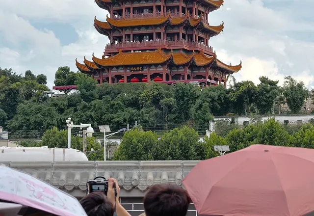 The tiered roofs of Yellow Crane Tower above trees and visitors in Wuhan