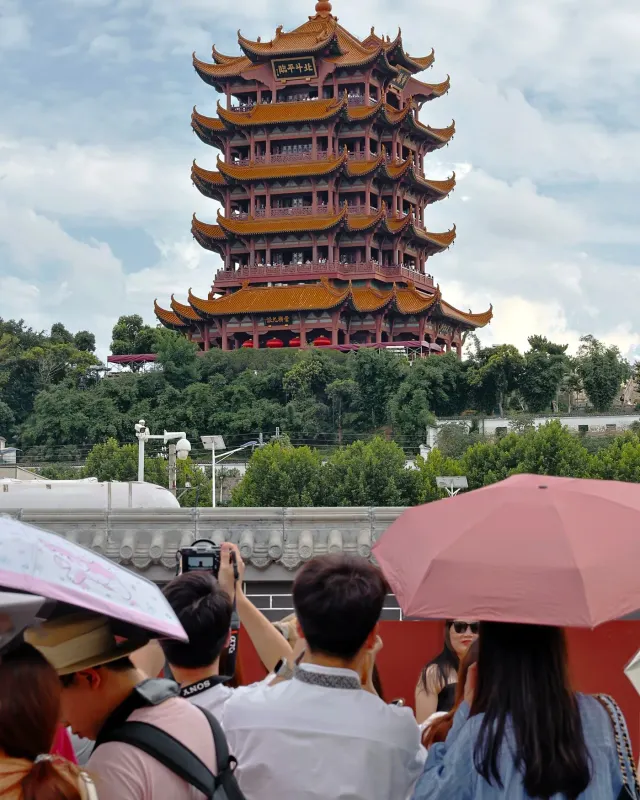 The tiered roofs of Yellow Crane Tower above trees and visitors in Wuhan